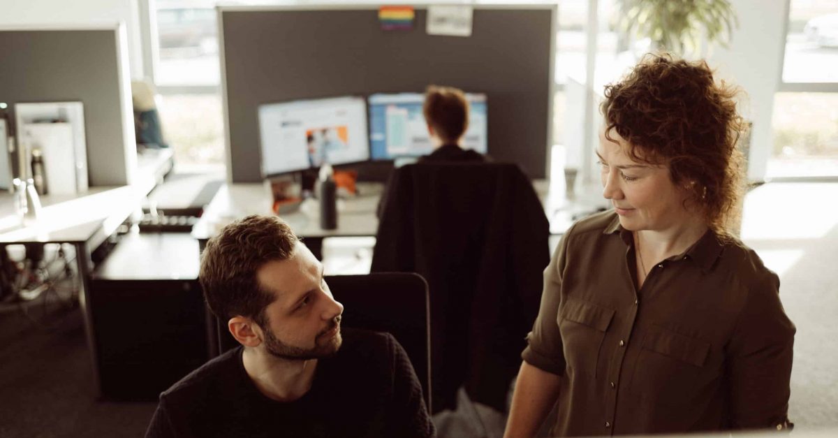 Kollegiales Gespräch zwischen zwei Mitarbeitenden in einem modernen Büro.