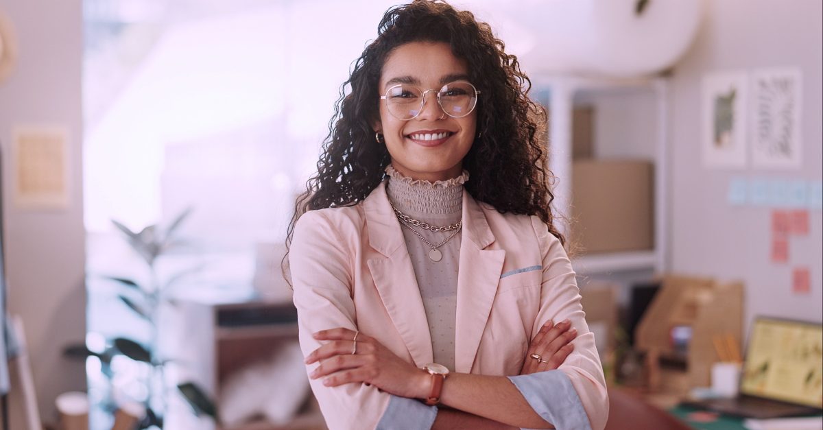Portrait, business woman and fashion designer with arms crossed in clothes store or startup. Confidence, happy tailor and face of professional, entrepreneur and creative worker in glasses in Brazil.
